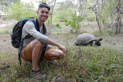 Ryan Grady kneeling near a tortoise during an education abroad trip