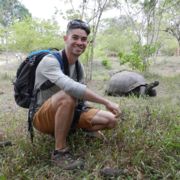 Ryan Grady crouched down near a large tortoise during his study abroad trip