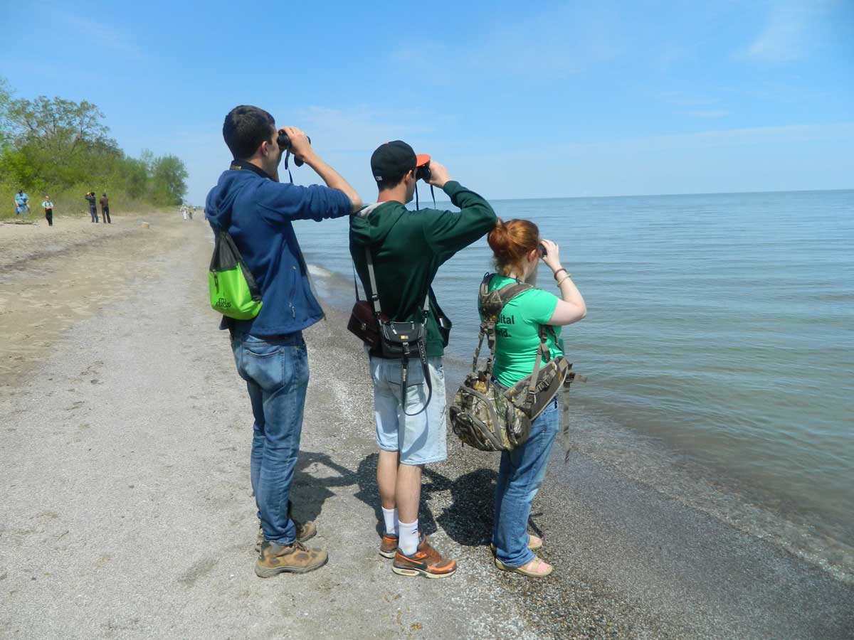 Members of the birding club at a beach looking into their binoculars to spot a spot